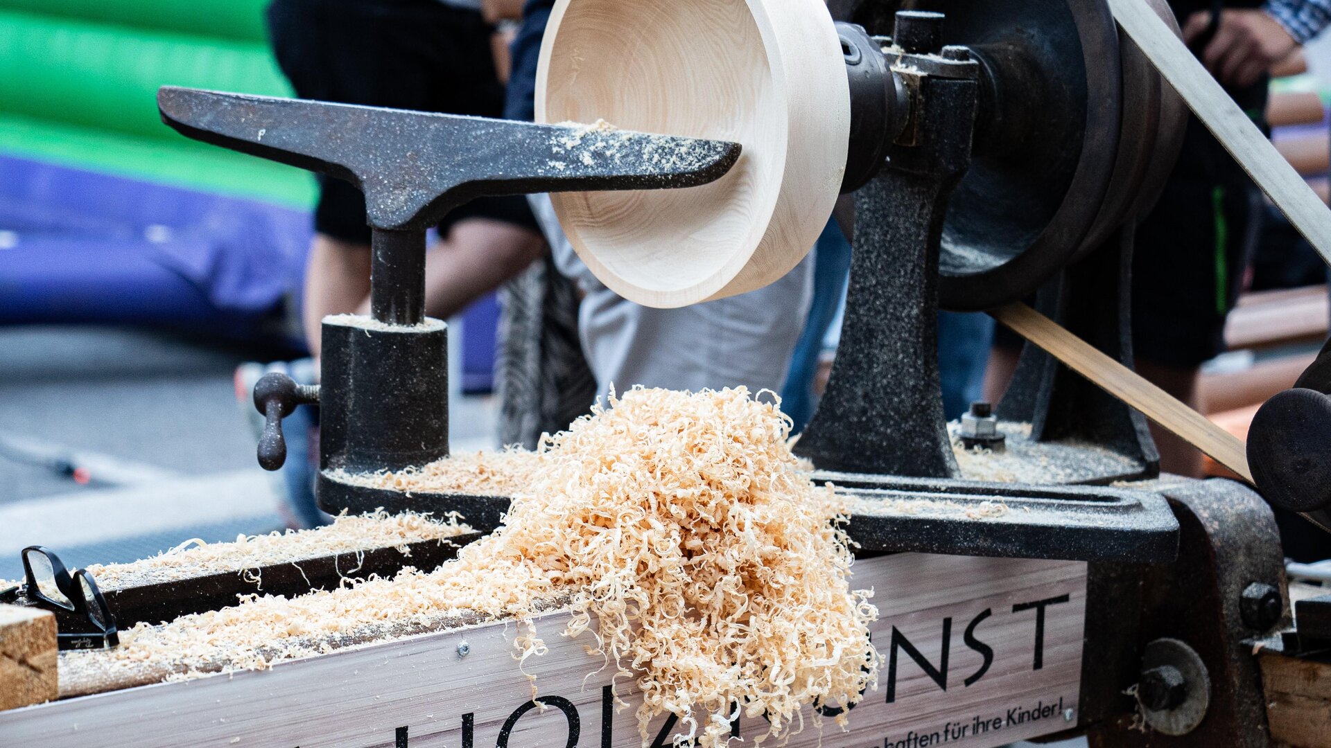 Eine Holzlathe wird verwendet, um eine Schüssel zu drechseln. Späne fallen von der Maschine auf den Boden.