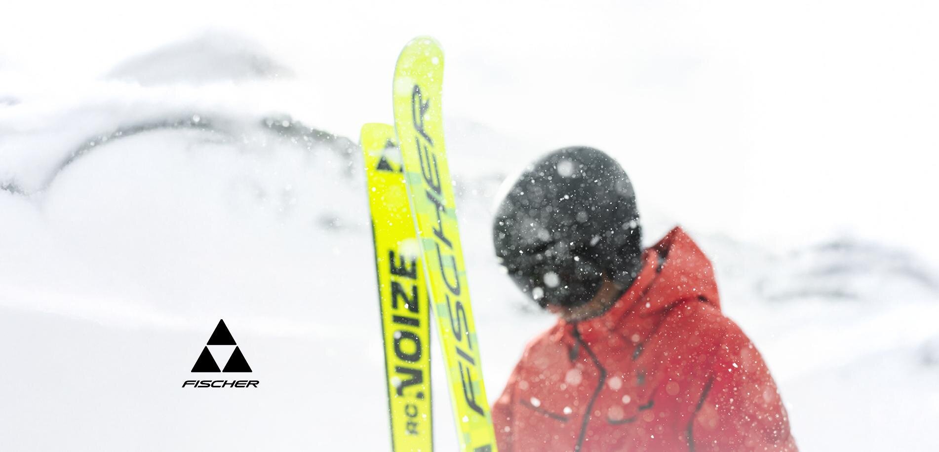 Ein Skifahrer steht im Schnee mit gelben Skiern. Die Umgebung ist winterlich und mit Schnee bedeckt.