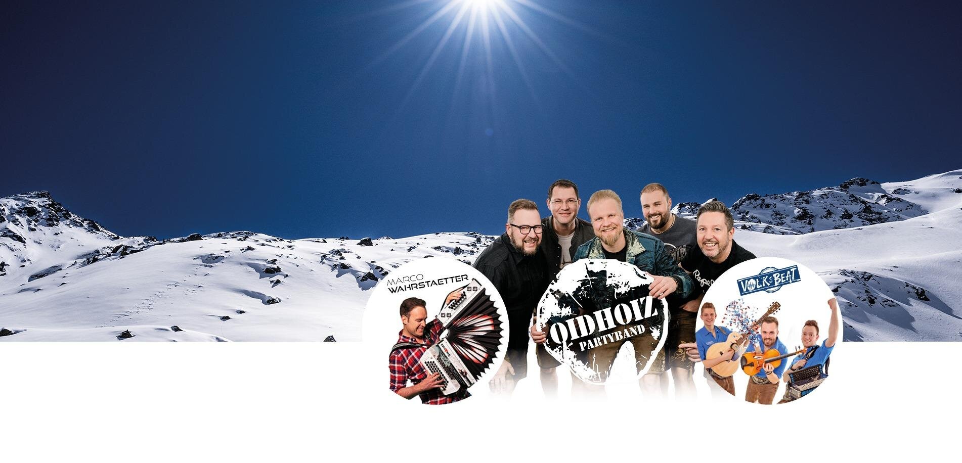 Eine Gruppe von Musikern steht vor einer verschneiten Berglandschaft. Im Hintergrund leuchtet die Sonne am klaren Himmel.