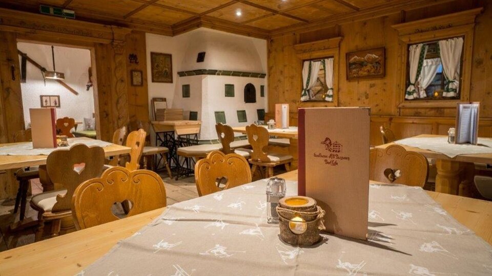 Ein gemütliches Restaurant mit Holzvertäfelung und rustikalen Tischen. Die Tische sind sauber gedeckt und es gibt eine einladende Atmosphäre.