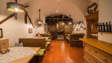Ein gemütliches Restaurant mit Holzmöbeln und warmem Licht. Die Wände sind traditionell gestaltet und schaffen eine einladende Atmosphäre.