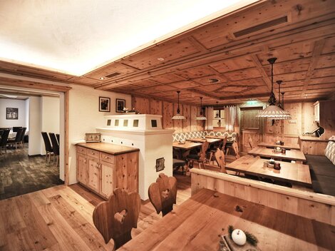 Ein gemütliches Restaurant mit Holzmobiliar und warmem Licht. Die Wände und Decken sind aus Holz, was eine einladende Atmosphäre schafft.