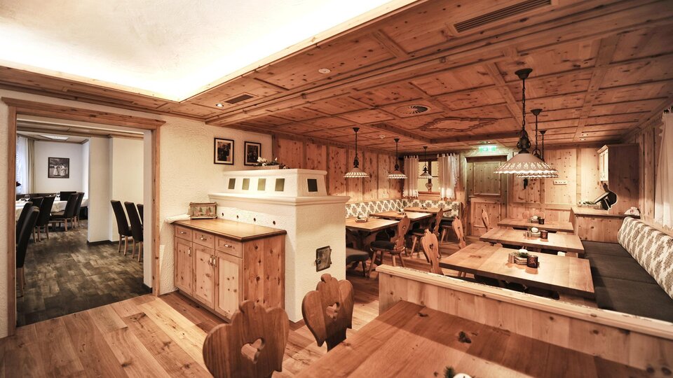 Ein gemütliches Restaurant mit Holzmobiliar und warmem Licht. Die Wände und Decken sind aus Holz, was eine einladende Atmosphäre schafft.