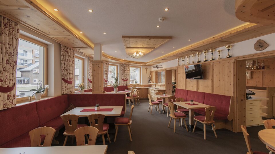 Ein gemütliches Restaurant mit Holzdekor und roten Polsterbänken. Es gibt Tische mit Platz für Gäste und große Fenster, die natürlichem Licht hereinzulassen.