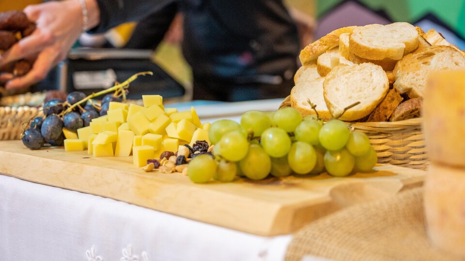 A beautifully laid table with fresh bread, cheese, grapes, and nuts. The colorful presentation invites you to enjoy.