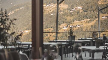Ein stilvolles Restaurant mit einem Blick auf die Berge. Die Tische sind elegant gedeckt und die Aussicht ist atemberaubend.