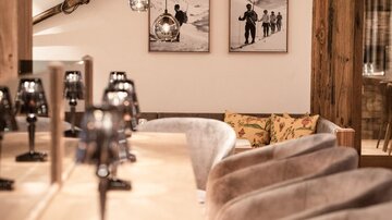 Ein gemütliches Restaurant mit Holzdekoration und bequemen Sitzplätzen. An der Wand hängen Schwarz-Weiß-Fotos von Personen im Schnee.