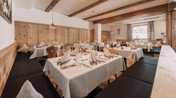 Ein einladendes Restaurant mit Holzwänden und elegant eingedeckten Tischen. Die Atmosphäre ist gemütlich und freundlich.