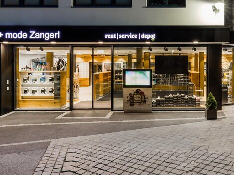 A sports store with large windows that showcases a variety of sports goods. The facade is modern and inviting, ideal for sports and fashion enthusiasts.