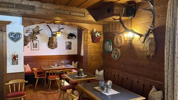 Ein gemütliches Restaurant mit Holzdekor und rustikalen Möbeln. Die Wände sind mit Jagdtrophäen und dekorativen Wandtellern geschmückt.