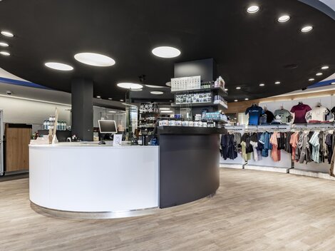 A modern sales area with a round reception desk and a clothing display. The walls are light-colored, and the lighting is friendly and inviting.