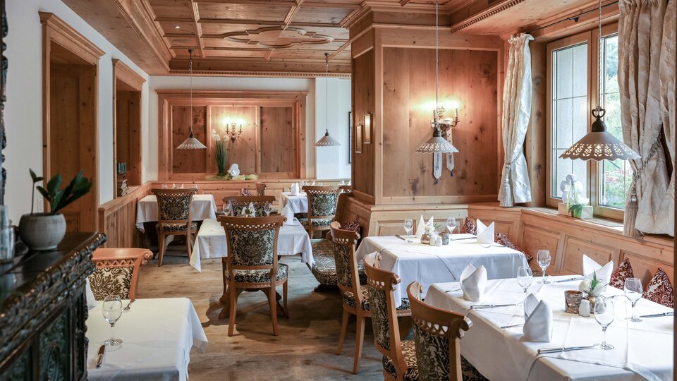 Ein gemütliches Restaurant mit Holzwänden und elegant eingedeckten Tischen. Sanftes Licht sorgt für eine einladende Atmosphäre.