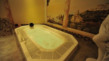 Ein elegantes Whirlpool in einem stilvollen Raum mit einer malerischen Wandmalerei. Die Atmosphäre ist entspannend und gemütlich.