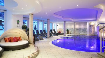 Ein eleganter Wellnessbereich mit einem blauen Pool und bequemen Liegen. Die Atmosphäre ist entspannend mit sanfter Beleuchtung und modernen Designelementen.