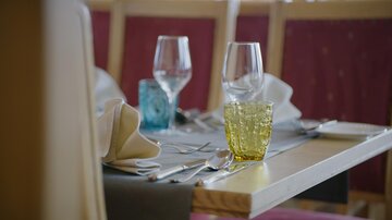 Ein elegant gedeckter Tisch in einem Restaurant. Es gibt Gläser, Besteck und dekorative Servietten.