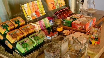 Ein Tisch mit verschiedenen Teesorten, Keksen und kleinen Behältern mit Zucker und Gewürzen. Die Anordnung wirkt einladend und gemütlich.