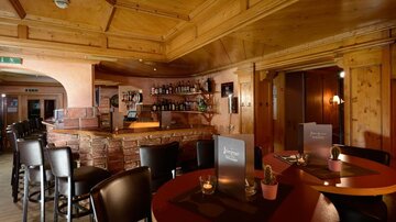 Eine gemütliche Bar mit Holzverkleidung und einer einladenden Atmosphäre. Die Tische sind vorbereitet und die Bar ist gut ausgestattet.