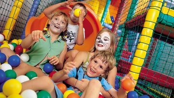 Vier Kinder spielen fröhlich in einem Ballbecken. Sie lachen und haben viel Spaß in einer bunten Spielumgebung.
