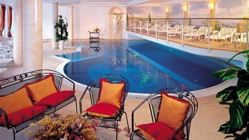 Ein stilvoller Innenpool mit gemütlichen Sitzecken und dekorativen Kissen. Lichtdurchfluteter Raum mit entspannendem Ambiente.