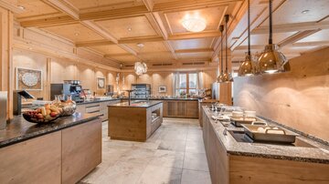 Eine moderne Küche mit Holzvertäfelung und eleganten Lichtanhängern. Die offenen Arbeitsflächen bieten viel Platz für die Zubereitung von Speisen.