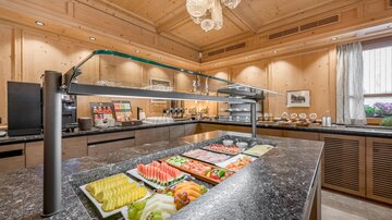 Ein eleganter Frühstücksbereich mit frischen Früchten und einer modernen Buffet-Anordnung. Die warme Holzverkleidung sorgt für eine einladende Atmosphäre.