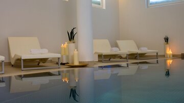 Ein eleganter Wellnessbereich mit Liegen und sanfter Beleuchtung. Der ruhige Pool reflektiert die entspannende Atmosphäre. | © Rössle