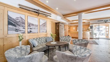 Ein eleganter Lounge-Bereich mit gemütlichen Sessel und einem runden Tisch. An den Wänden hängen Bilder von Bergen und die Atmosphäre ist einladend. | © Rössle