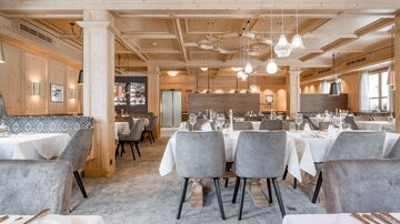 Ein elegantes Restaurant mit hellen Holzelementen und stilvollen Tischdeckungen. Die Atmosphäre ist einladend und modern.