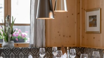 Ein elegantes Restaurant mit einem schön gedeckten Tisch. Die Wände sind aus hellem Holz, und es hängen stilvolle Lampen von der Decke.