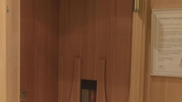 Eine gemütliche Sauna aus Holz mit einer Bank und einer Heizvorrichtung. Die Wände sind schlichte, helle Holzpaneele.