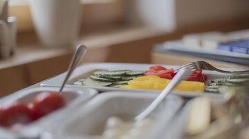 Ein gedeckter Tisch mit frischem Gemüse. Auf dem Teller sind Gurken, Paprika und Tomaten schön angerichtet.