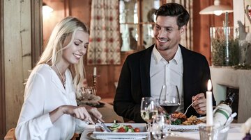 A stylish dinner in a cozy restaurant. A couple is enjoying a meal and having a pleasant conversation.