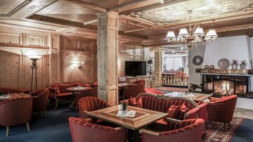 A cozy lounge with wooden walls and red armchairs. The fireplace creates a pleasant atmosphere.