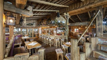 A cozy restaurant with wooden interiors and rustic charm. The seating and decorations create an inviting atmosphere.
