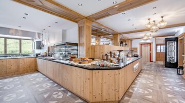 A modern kitchen with wooden paneling and a large countertop. The room is bright and inviting, perfect for cooking and dining together.