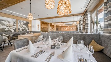 An elegant restaurant with stylish lamps and a cozy atmosphere. Tables are set with white tablecloths and fine china.