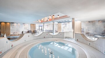 An elegant wellness area with a round hot tub. Bright colors and modern furnishings create a relaxing atmosphere.