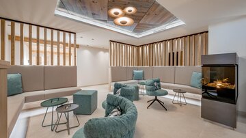 A modern lounge area with cozy seating and warm lighting. The walls are made of wood and the atmosphere is inviting and relaxed.