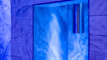 A modern wall area with a illuminated blue panel. The stone creates an elegant atmosphere.