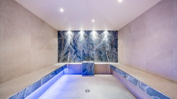 A modern spa with elegant design and soft lighting. The walls are clad with high-quality materials, creating a relaxing atmosphere.