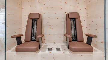 Two modern brown chairs in a bright wooden room. The walls are made of light wood, creating a relaxing atmosphere.
