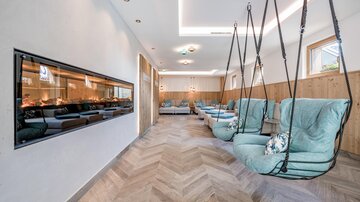A stylish room with hanging chairs and a modern fireplace. The wood paneling and soft colors create a relaxing atmosphere.