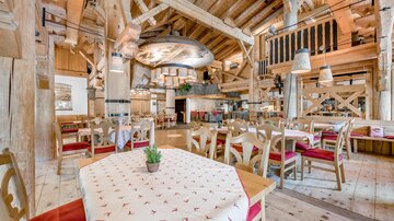 A cozy restaurant with rustic wooden design.  
Tables with red seats and an inviting atmosphere.